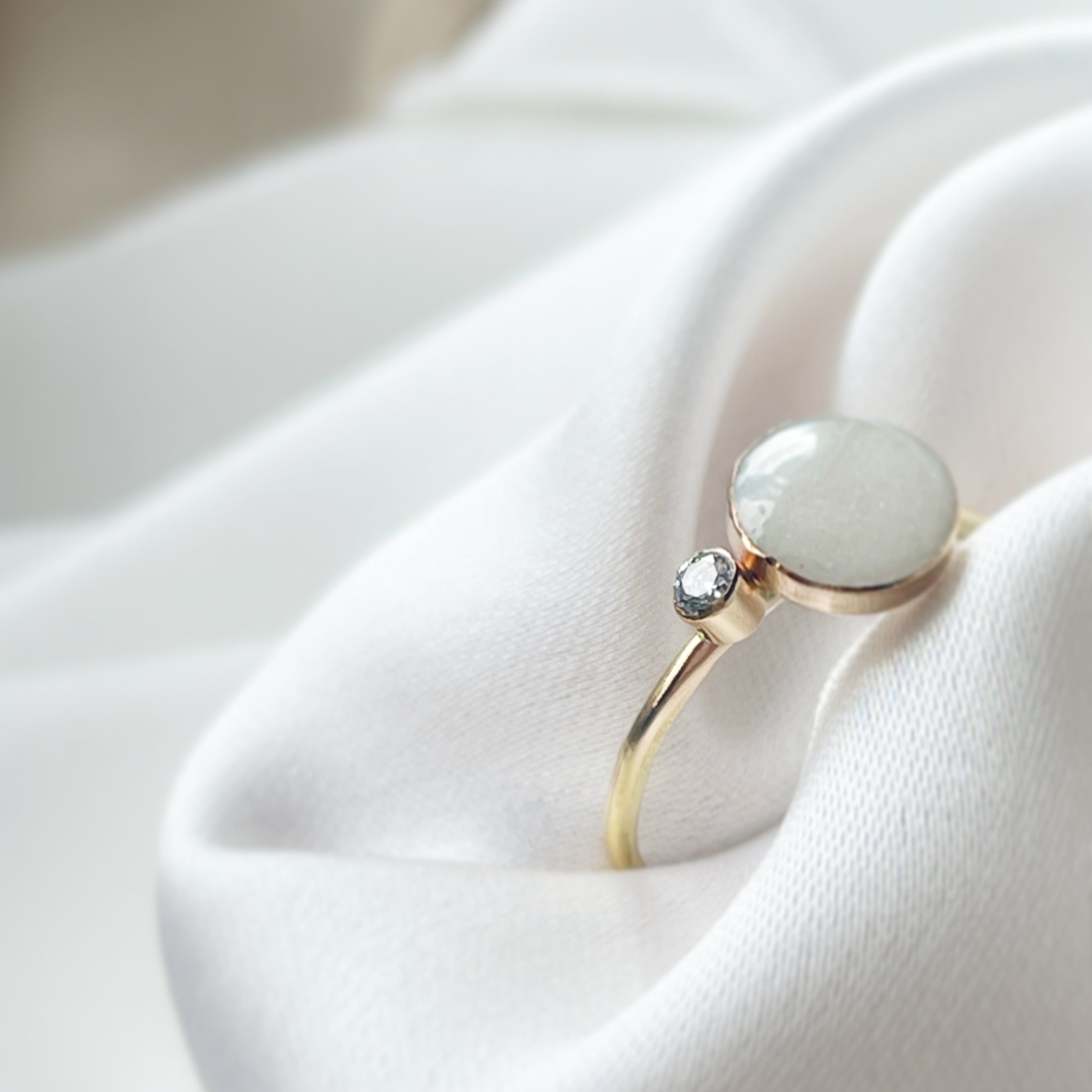 Gold ring with a light-colored gemstone on a white fabric background