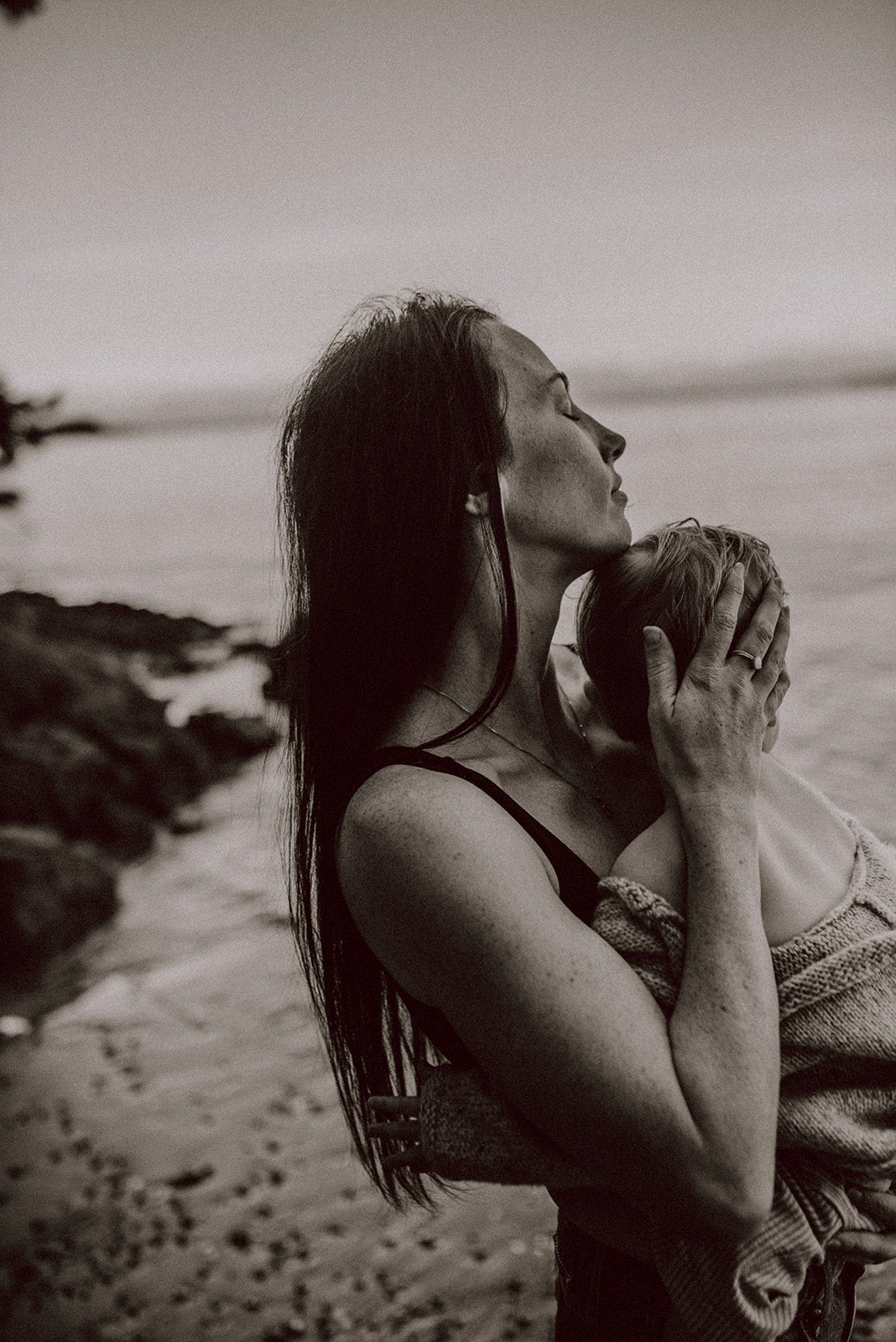 Woman holding a child close to her face on a beach
