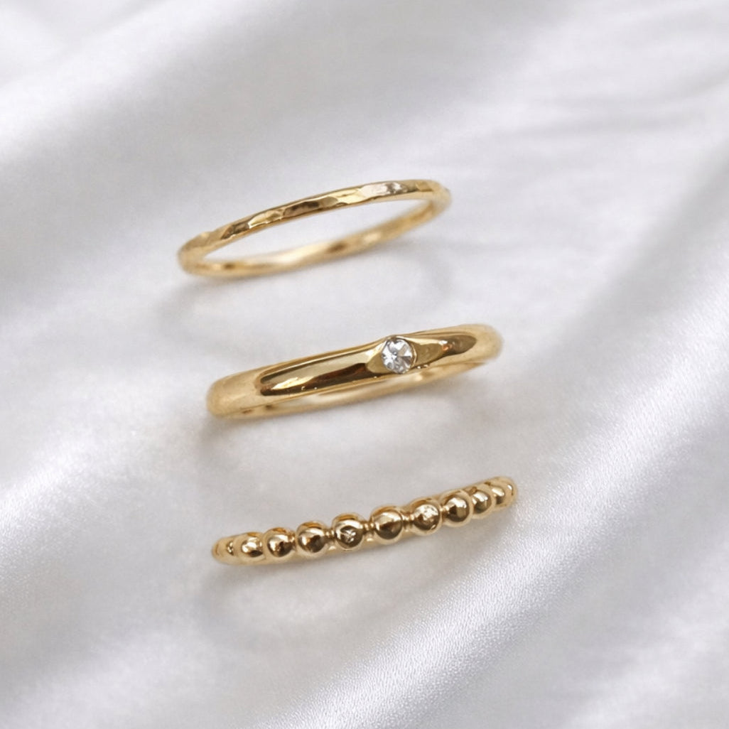 Three gold rings on a white satin background