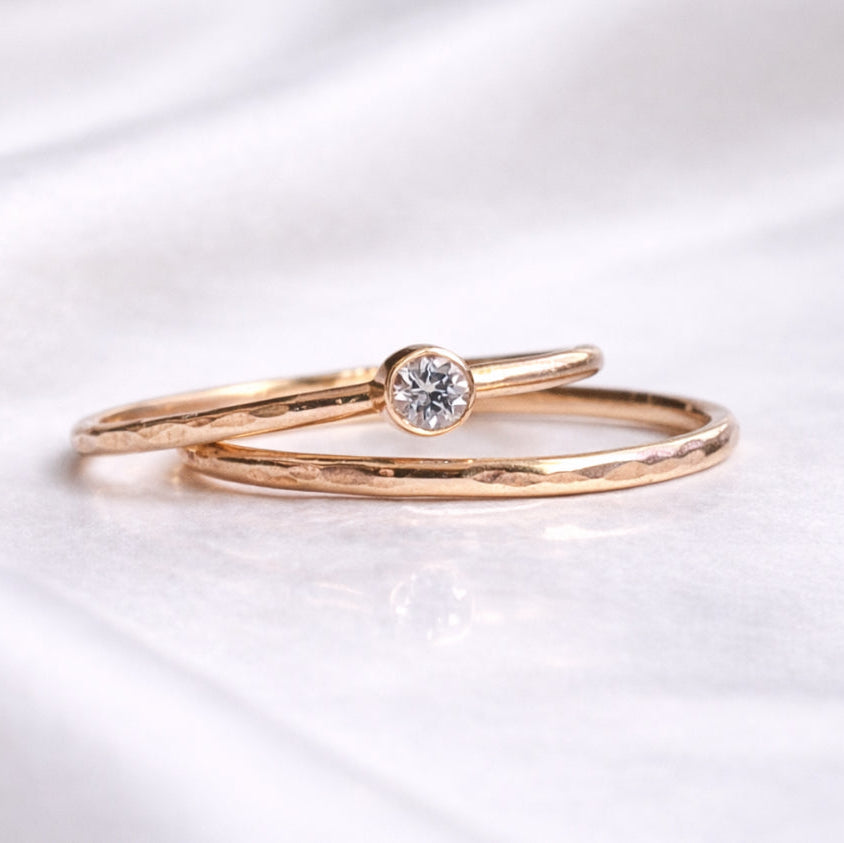 Rose gold ring with a diamond on a white satin background