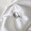Silver ring with fingerprint design on a white satin background