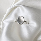 Silver ring with fingerprint design on a white satin background