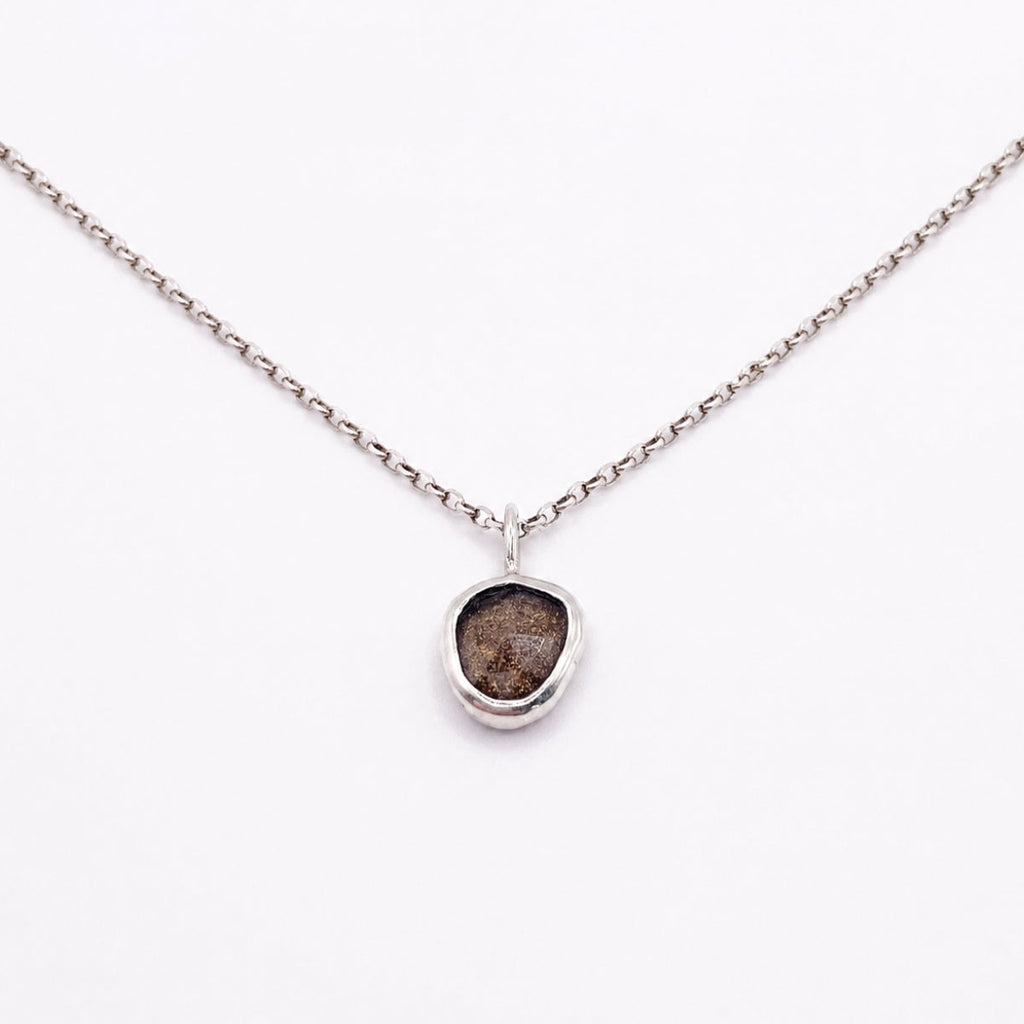 Necklace with a pendant featuring a rough diamond on a white background