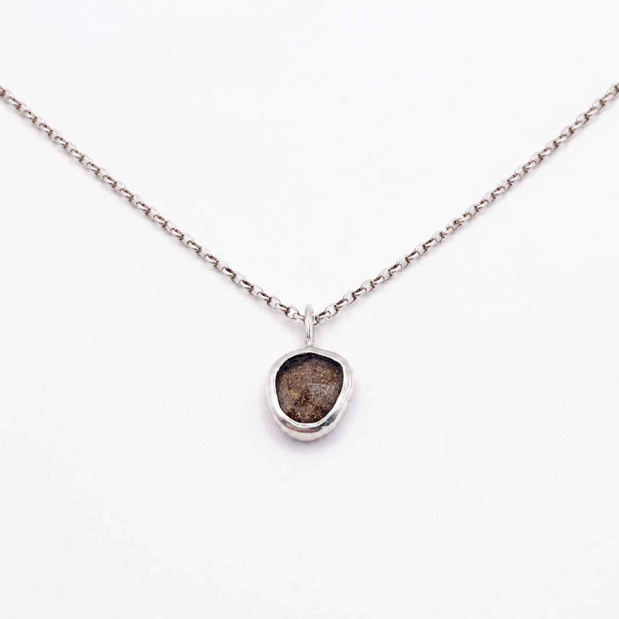 Necklace with a pendant featuring a rough diamond on a white background
