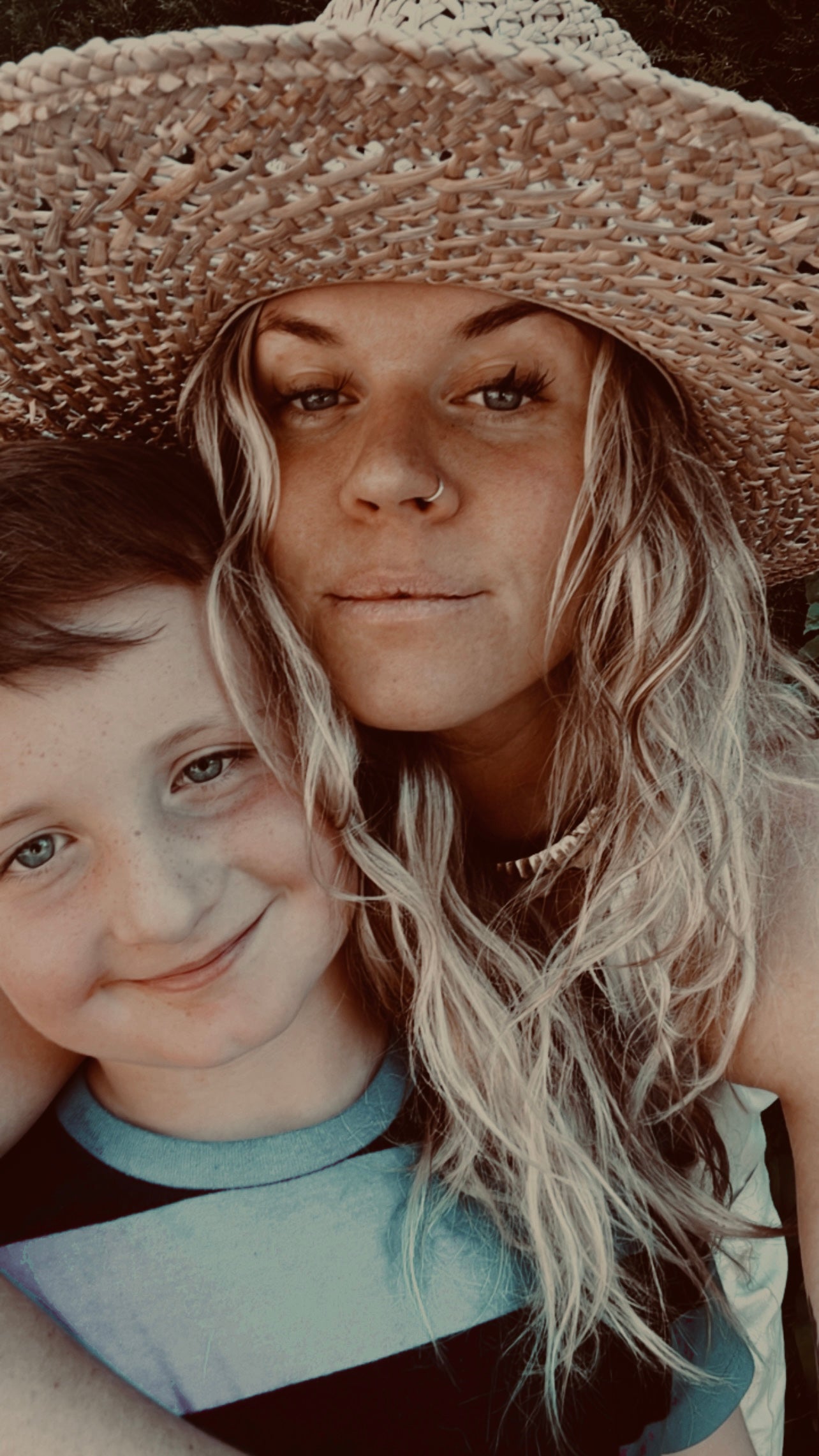 Woman and child wearing straw hats, smiling at the camera.