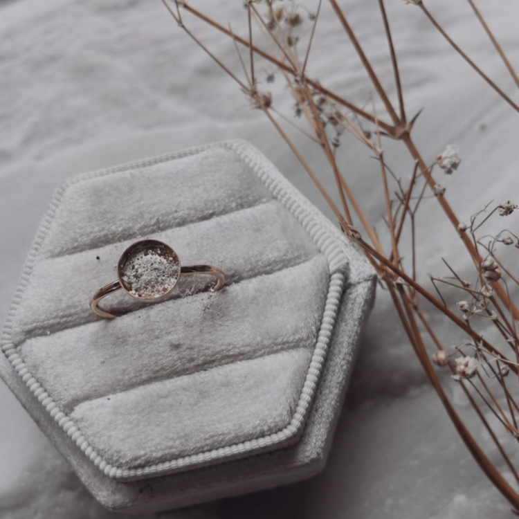 a ring box, with a casing for a gem with cremation ashes dusted in the setting